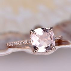 an engagement ring with a pink diamond in the center on top of a white shell