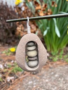 a rock hanging from a wire with stones in the shape of a flower and leaves