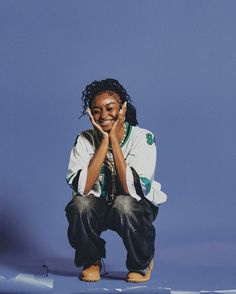 a man sitting on the ground with his hands to his face, smiling and looking at the camera