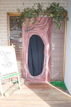 a wooden floor next to a brick wall with a plant growing out of the door