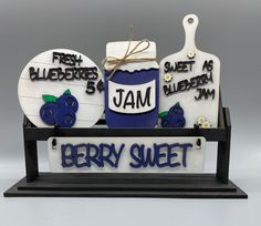 there is a sign that says jam and two blueberries on it with a jar