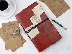 a red notebook sitting on top of a white table next to a cup of coffee