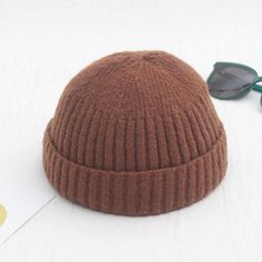 a brown knitted hat and sunglasses on a white surface with a yellow sticker next to it