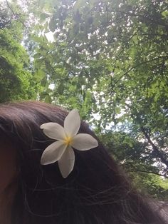 a woman with long brown hair and a white flower in the middle of her hair