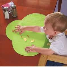 a young boy sitting at a table with his hands on a green plate that is shaped like a flower