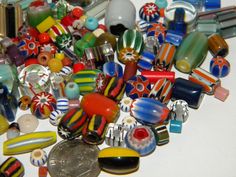 a pile of colorful glass beads sitting on top of a white table next to a coin