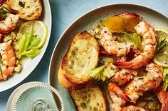 two plates with shrimp, bread and vegetables on them next to a glass of water