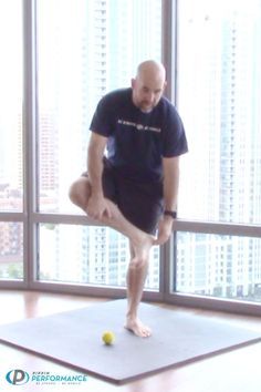 a man standing on one leg in front of a window doing a yoga pose with a ball