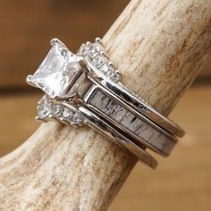 two wedding rings sitting on top of a piece of wood with diamonds in the middle