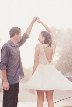 a man and woman standing in the rain holding hands