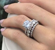 a woman's hand with two rings on her fingers and one ring in the middle