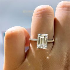 a woman's hand with a ring on it and an emerald stone in the middle