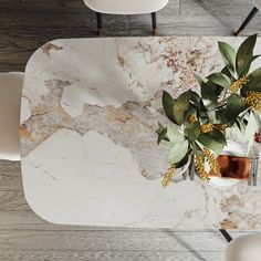 a marble dining table with white chairs and flowers on it, viewed from up above