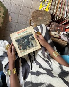 a woman sitting on the floor reading a book with an old record in front of her