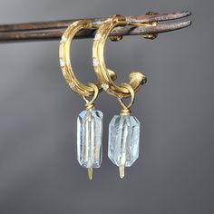 Free-form faceted aquamarines delicately hang on beautiful hoops. These handcrafted 18k gold hoops are half round on the inside, and on the outside there is a thin 'arch', slightly hammered and set with 5 luminous white diamonds on each earring. Understated chic you can wear everyday, and for every occasion. The charms can be removed from the hoops. You can wear the hoops alone, or with other charms on them. Please note, the raw aquamarine stones are not exactly alike, being natural as they are, Bench Jeweler, Hoops With Charms, Christmas Circle, Raw Aquamarine, Artist Working, Earrings Hoops, Aquamarine Earrings, Birthstone Earrings, Earrings Diamond