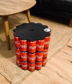 a stack of coca - cola cans sitting on top of a rug next to a table