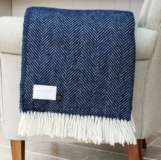 a blue and white herringbone throw sitting on top of a chair