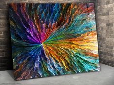 an abstract painting on the wall in a room with brick walls and concrete flooring