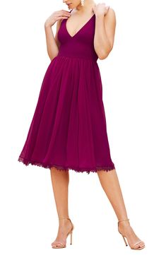 a woman in a purple dress is posing for the camera with her hand on her hip