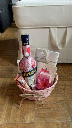 a bottle of liquor sitting in a basket on the floor next to a box with soaps and other items