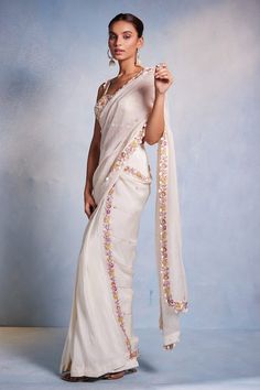 Off white padded blouse featuring floral hand embroidery all over with shell tassels on the waist hem. Paired with a hand embroidered pre-draped saree. - Aza Fashions White Pre-draped Saree With Floral Embroidery, Embroidered Fitted Saree, Embroidered Fitted Draped Saree, Elegant Fitted Saree With Floral Embroidery, White Silk Pre-draped Saree In Traditional Style, Festive Fitted Pre-draped Saree With Floral Embroidery, Festive Fitted Floral Embroidered Pre-draped Saree, White Georgette Pre-draped Saree With Floral Embroidery, Designer White Pre-draped Saree With Floral Embroidery