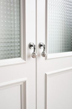 two white double doors with chrome handles and glass panels on the front door are shown