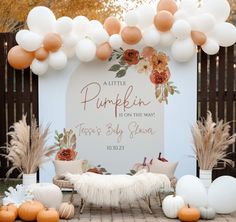 an outdoor pumpkin themed baby shower with white and orange balloons in the shape of pom poms