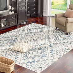 a living room filled with furniture and a rug on top of a hard wood floor