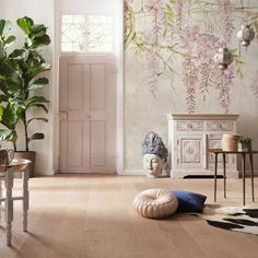 a living room filled with lots of furniture next to a wall covered in pink flowers