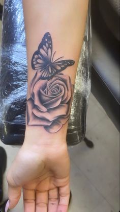 a woman's hand with a tattoo on it that has a rose and a butterfly on it