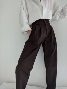 The Na Nin Townes Trousers are inspired by classic 90s style and can be worn in many ways throughout the seasons. Made with lightweight cotton, they are durable, yet allow for movement and feature a relaxed waistline that can be worn high or low on the waist. The thoughtful details of these trousers include pockets, belt loops, cuffs and double pleats. For an elegant classic look, pair with our Fiona Top in cotton poplin and your favorite gold pieces from our In House Jewelry Line. Made In USA Classic Baggy Pants For Fall, Classic Brown Bottoms For Everyday, Classic Baggy Bottoms For Spring, Classic Baggy Bottoms For Everyday, Modern Cotton Bottoms For Daywear, Modern Cotton Pants For Fall, 00s Mode, Academia Outfits, Mode Costume