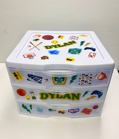 a white plastic box with many different stickers on the lid and bottom, sitting on a table