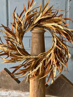 a close up of a wooden pole with a wreath on it's end and an old door in the background