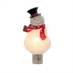 a snowman night light with a red scarf and hat on it's head