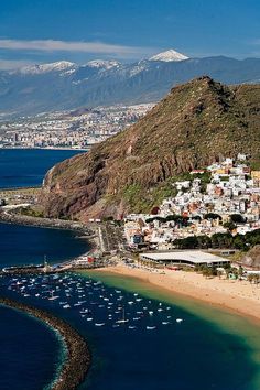 an aerial view of a beach with boats in the water and mountains in the background