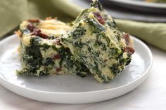 two pieces of spinach and cheese quiche on a white plate next to green beans