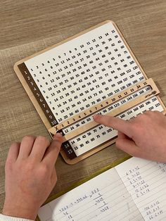 a person using a wooden crossword puzzle on a table with several sheets of paper