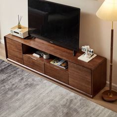 a flat screen tv sitting on top of a wooden entertainment center next to a lamp