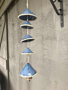 a wind chime hanging from the side of a building with blue shades on it