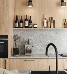 a kitchen with wooden cabinets and marble counter tops, black faucet in the foreground