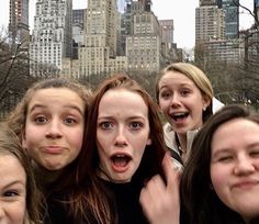 a group of young women standing next to each other in front of a city skyline