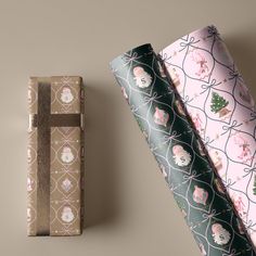 two wrapping paper rolls next to each other on top of a brown surface with pink and green designs