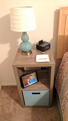 a nightstand with an alarm clock on it next to a night stand and a lamp