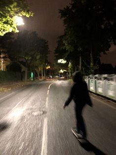 a person riding a skateboard down a street at night