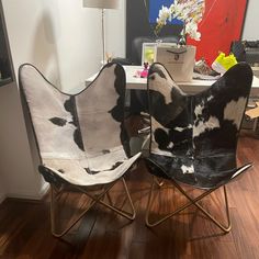 two black and white chairs sitting on top of a hard wood floor