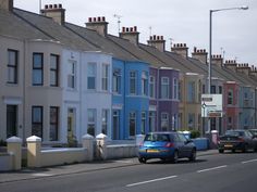 cars are parked on the street in front of row houses with blue and white sidings