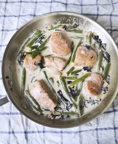 a pan filled with green beans and seared scallops covered in white sauce