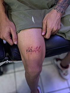 a person sitting in a chair with their legs crossed and writing on the side of his leg