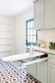 an ironing board in the middle of a kitchen with blue and white tiles on the floor