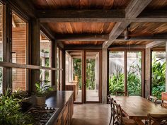 an open kitchen and dining area with wood paneled walls, wooden flooring, and large windows